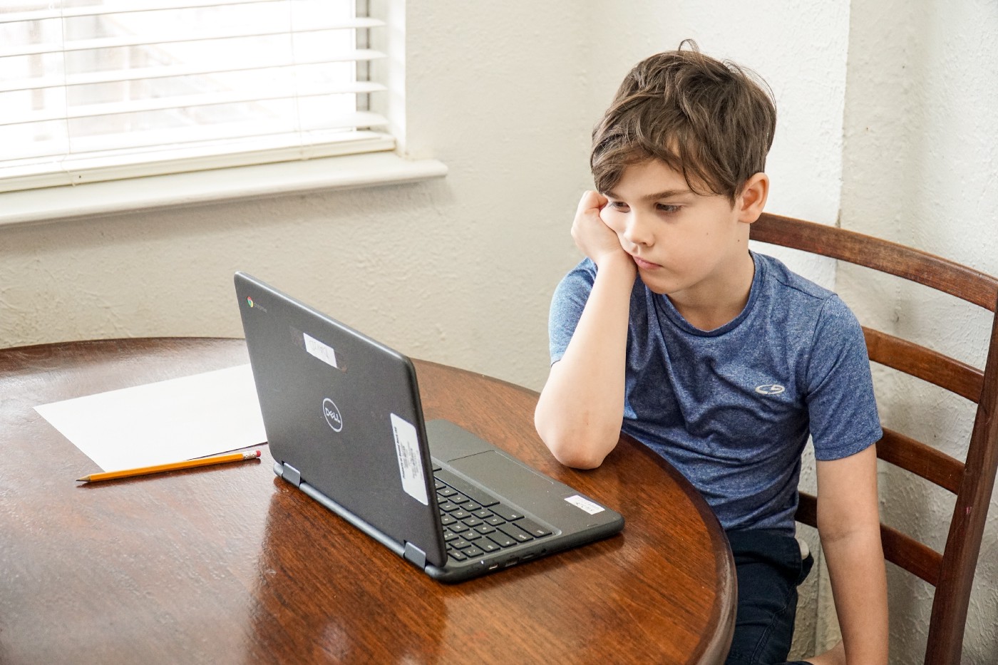 Seorang anak kecil melihat laptopnya dengan kebosanan tak terbatas dari seorang pria yang jauh lebih tua.