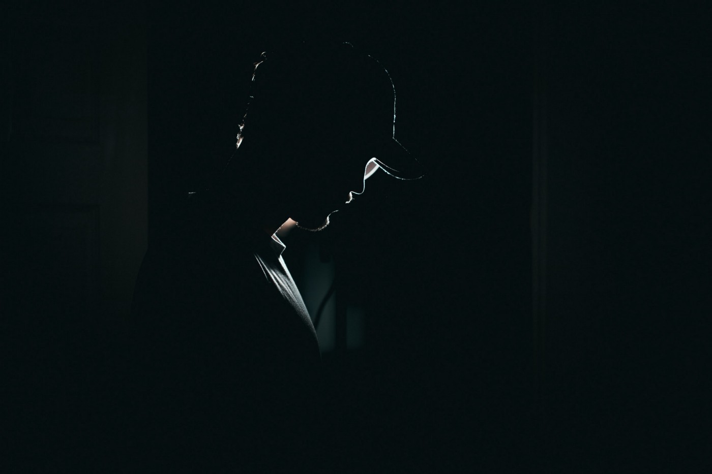 Seorang pria berdiri dalam kegelapan.  Kita tidak bisa melihat wajahnya.